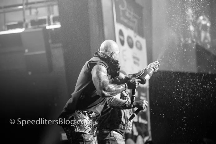 Black-and-white concert photo of Flo Rida spraying champagne over the crowd on stage
