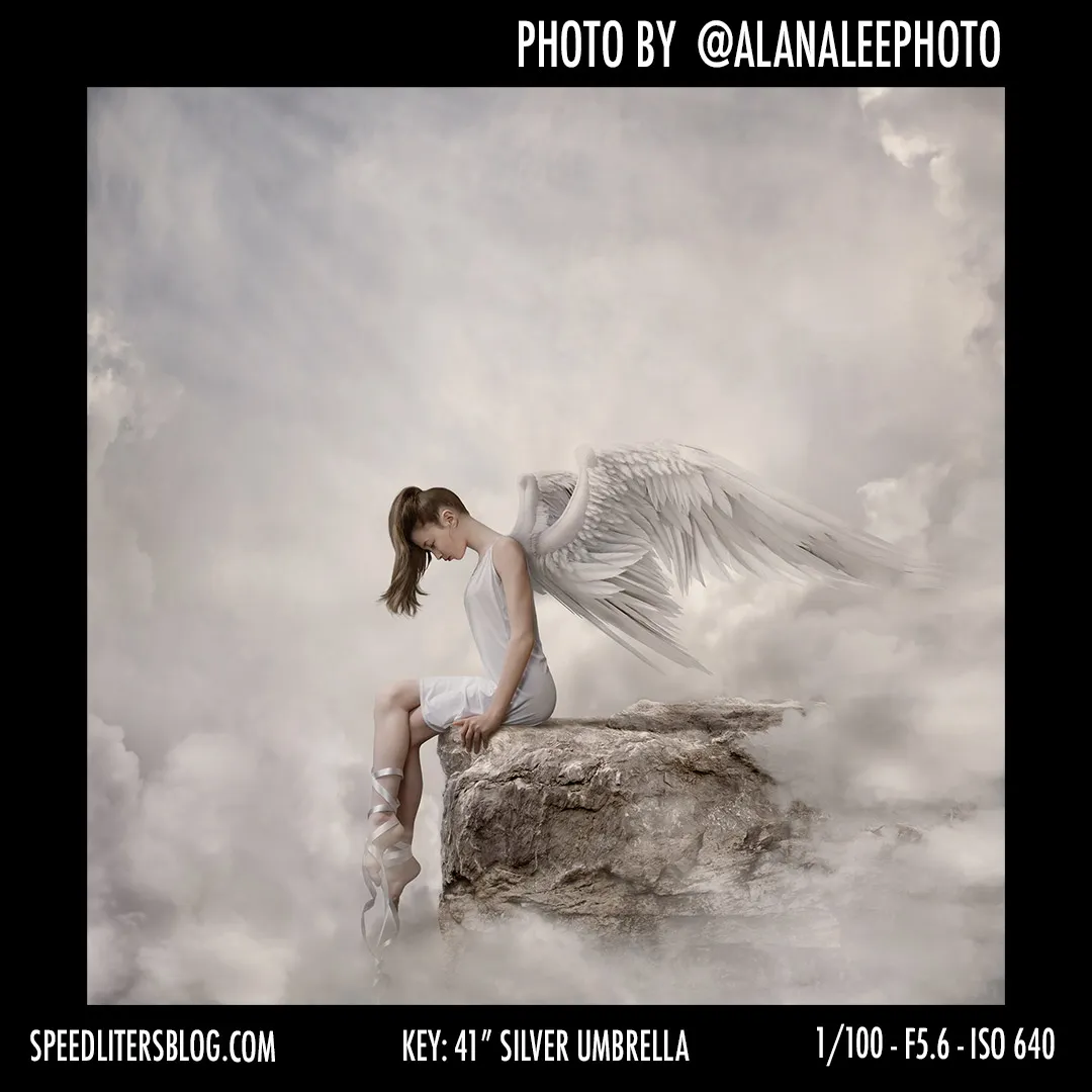 Ballerina with angel wings sitting on a rock among clouds, a fine art composite by Alana Lee