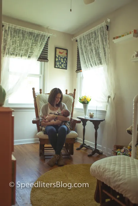 Mother feeding her newborn in a rocking chair in a sunlit nursery