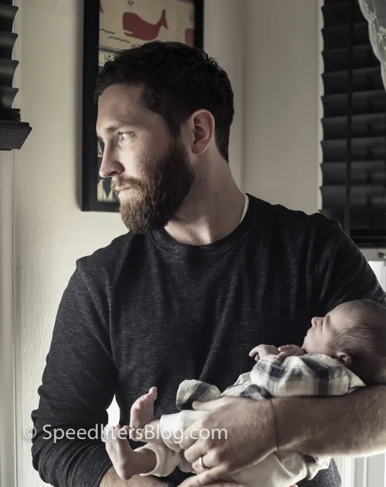 Bearded father holding his newborn daughter by a window