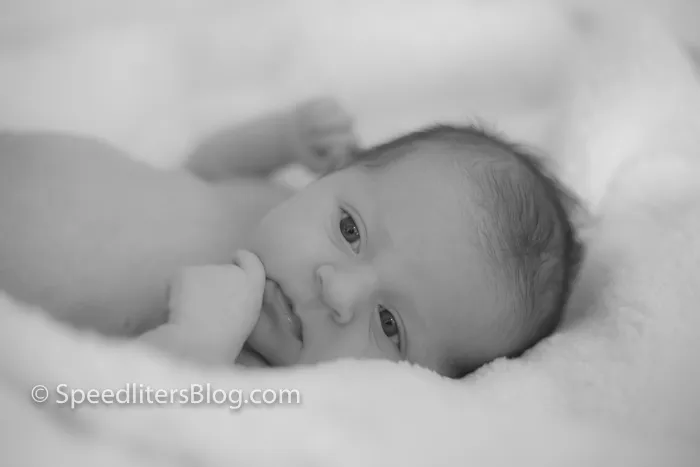 Black-and-white close-up of a newborn lying on a soft blanket