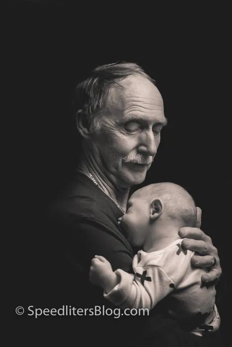 Grandfather holding a sleeping baby, black-and-white portrait lit by one softbox