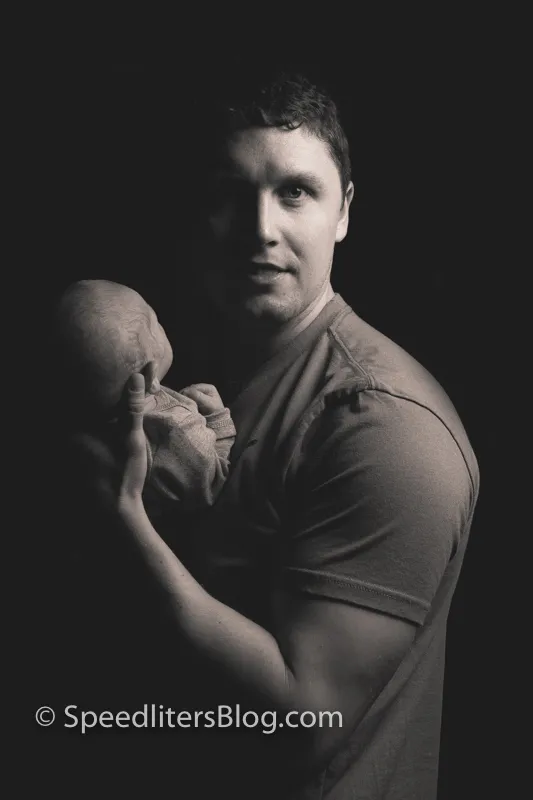 Father holding his baby against his shoulder, black-and-white one-light portrait