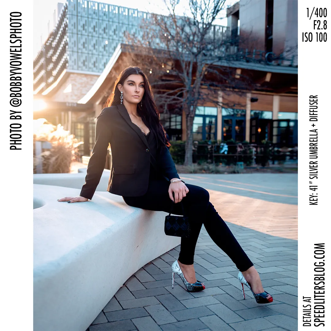 Woman in a black suit sitting on a curved bench in an outdoor plaza, by Bobby Vowels