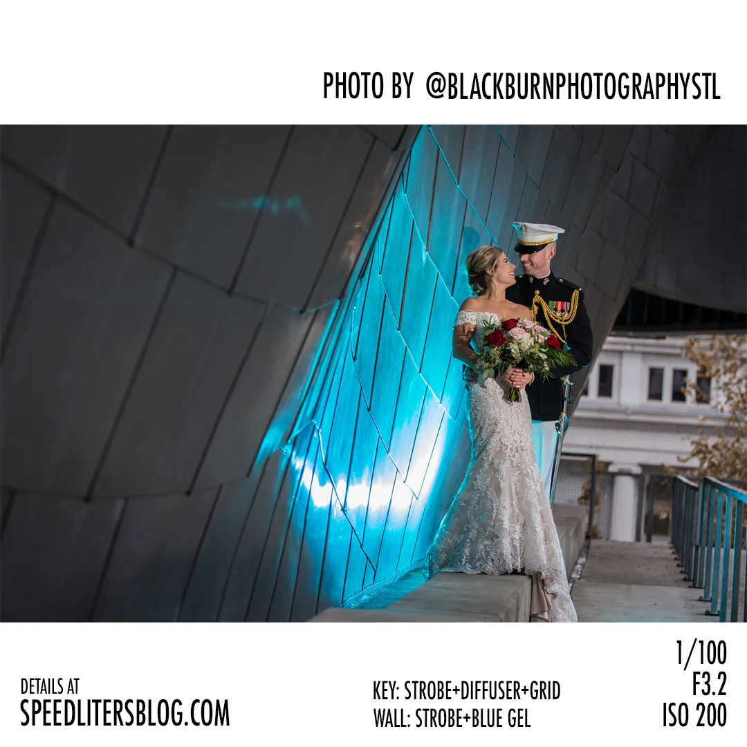 Bride and Marine groom embracing beside a modern building wall lit with a blue gel, by Brad Blackburn