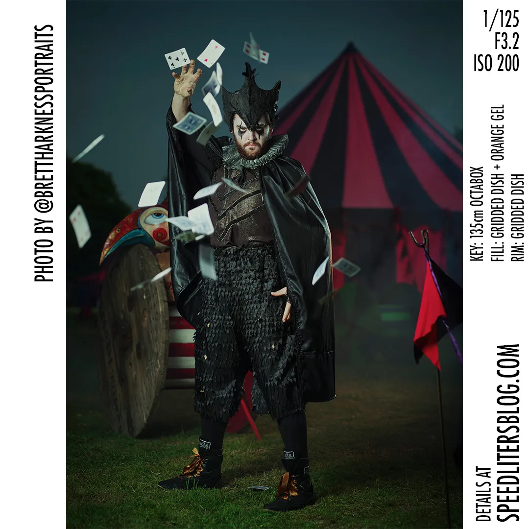 Performer in a dark costume throwing playing cards in front of a red circus tent, by Brett Harkness
