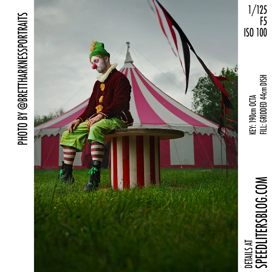 Sad clown sitting on a striped drum in front of a circus tent, by Brett Harkness