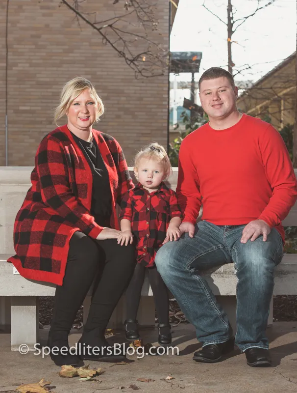 Family in matching red plaid sitting on a bench outdoors in fall
