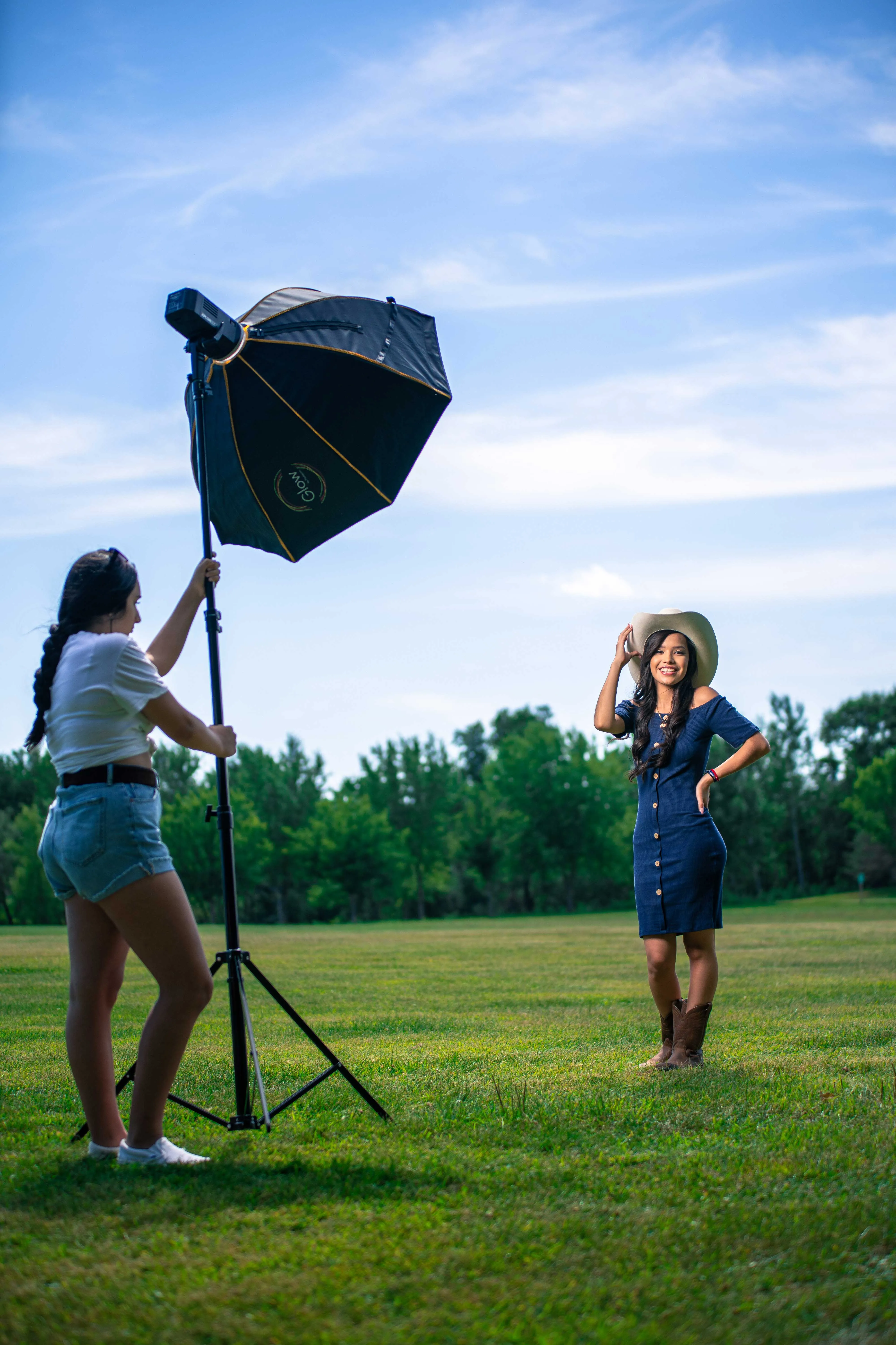 Behind the scenes: assistant holding an octabox on a stand for a senior in a cowboy hat