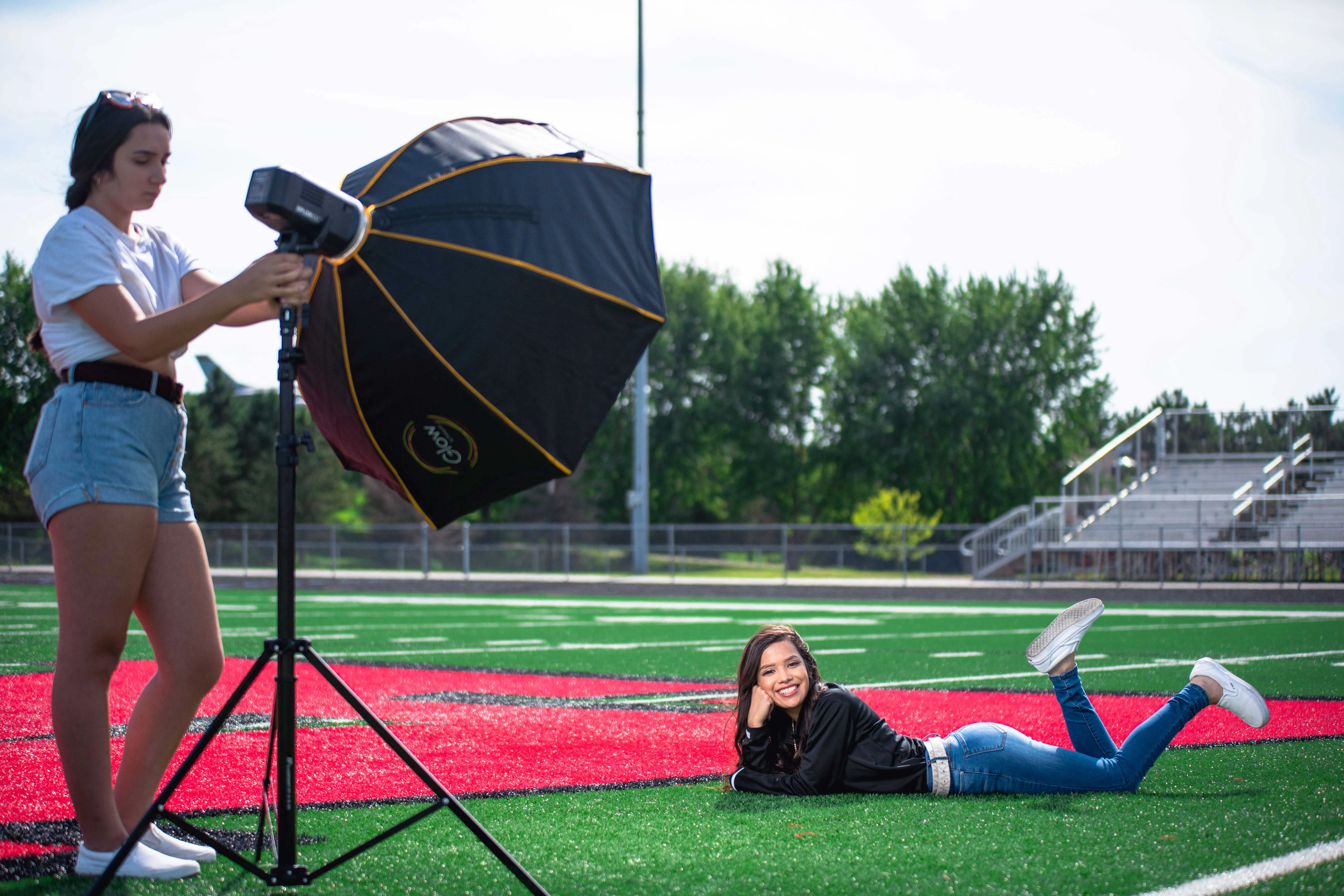 Behind the scenes: assistant positioning an octabox while a senior lies on a football field