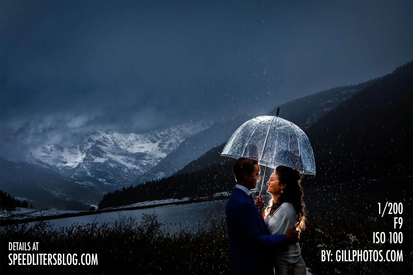 Couple under a clear umbrella at dusk in the rain with mountains behind, by Gillespie Photography