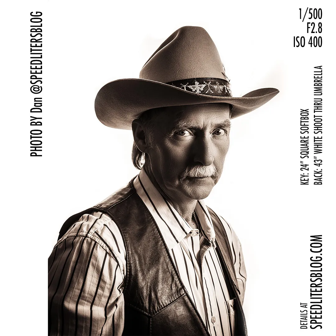 Older man in a cowboy hat and leather vest against a white background, dramatic sepia portrait
