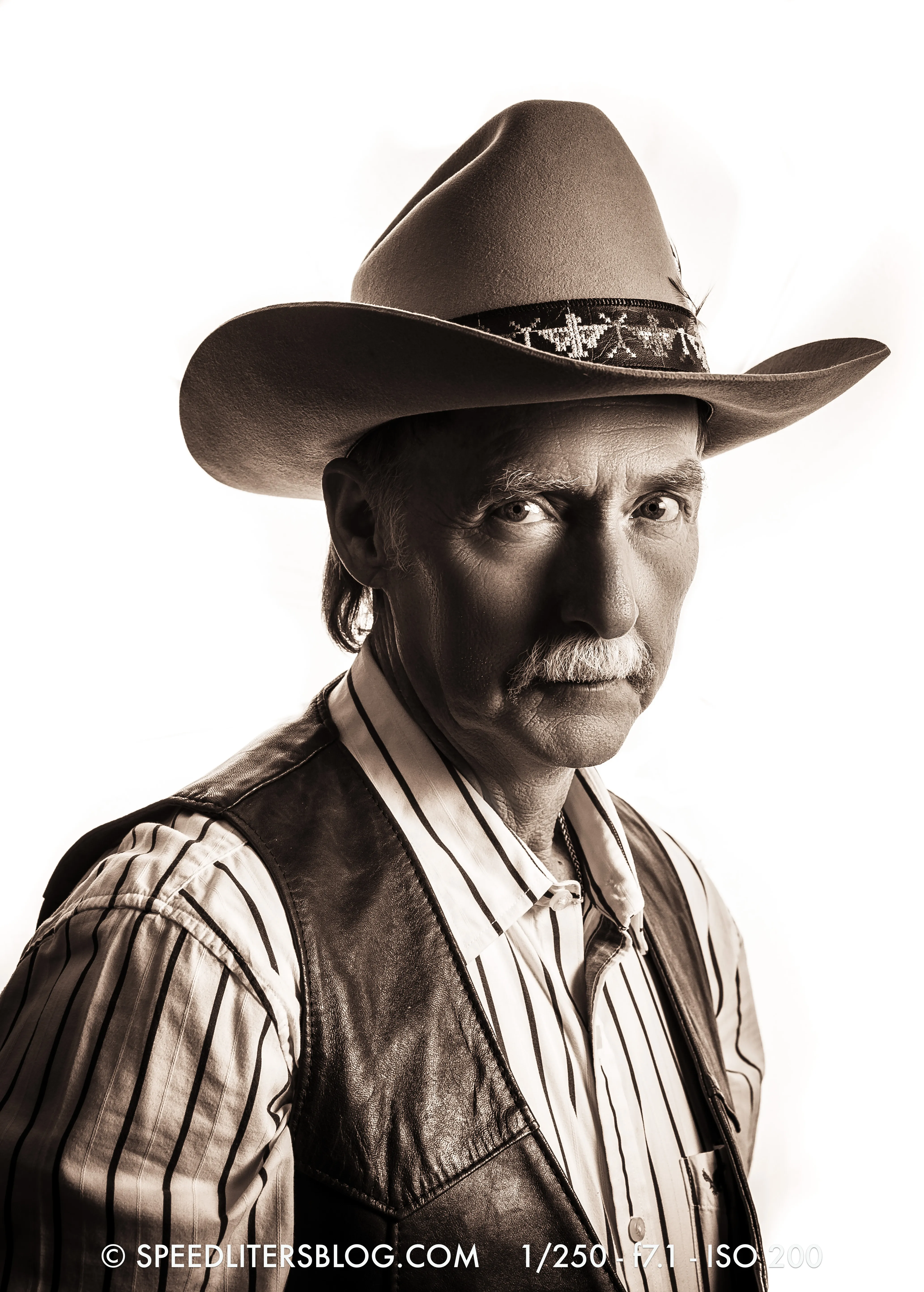 Sepia portrait of an older man in a cowboy hat on a white background