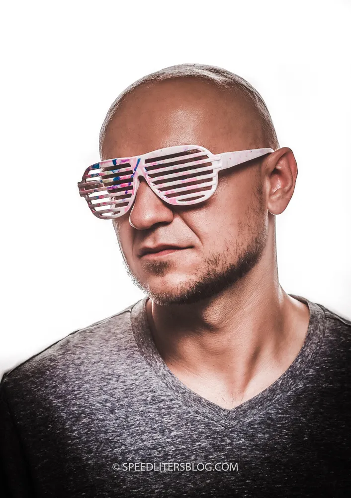 Man in shutter shades against a white background, lit by a softbox