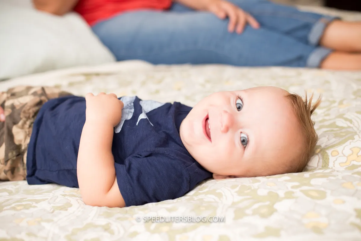 Smiling baby lying on his side on a bed