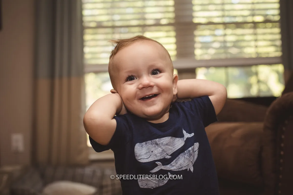 Laughing one-year-old with his hands behind his head