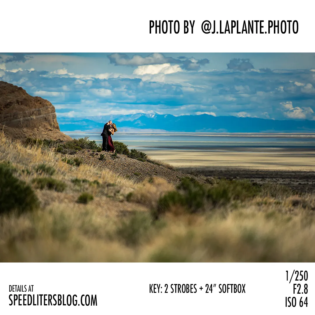 Couple standing on a ridge overlooking a vast desert basin, by J La Plante