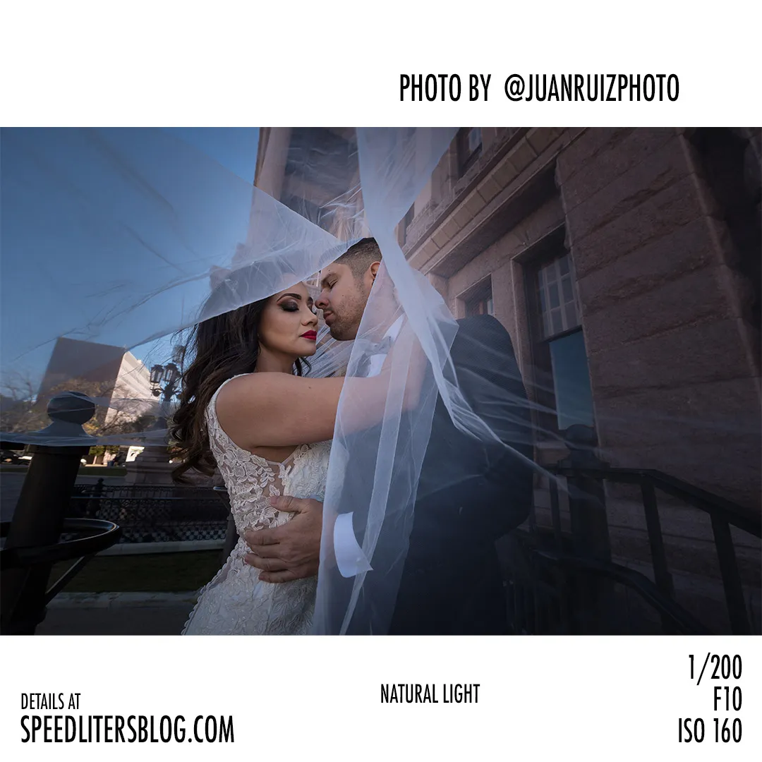 Bride and groom wrapped in her veil in open shade, by Juan Ruiz