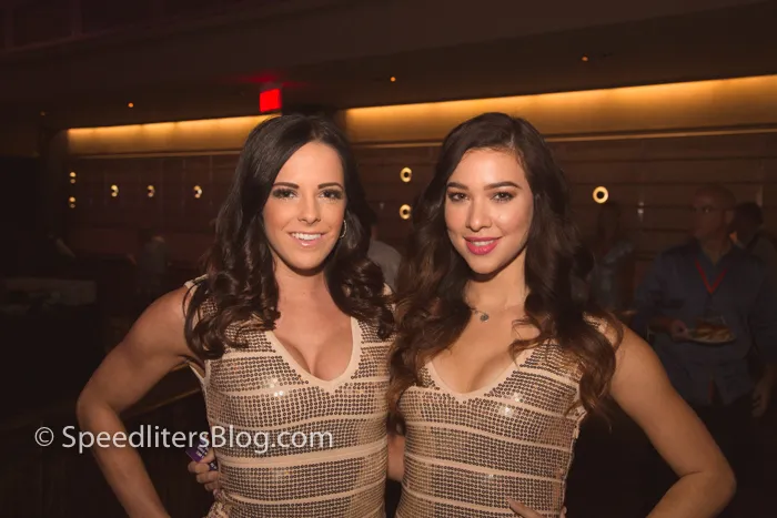 Two women in sequined tops posing at a party, lit by flash