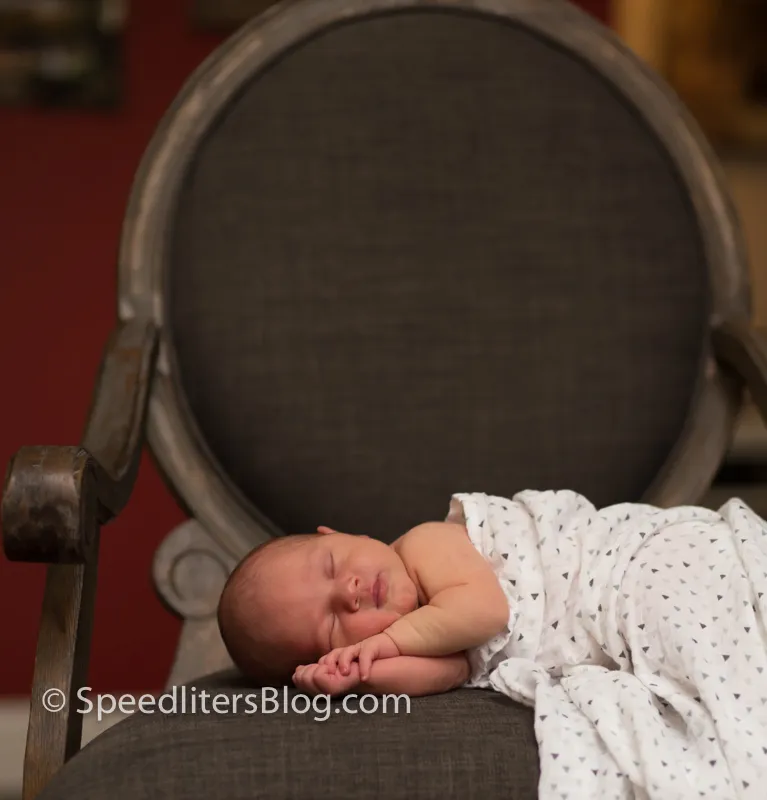 Newborn sleeping on a chair under a white blanket