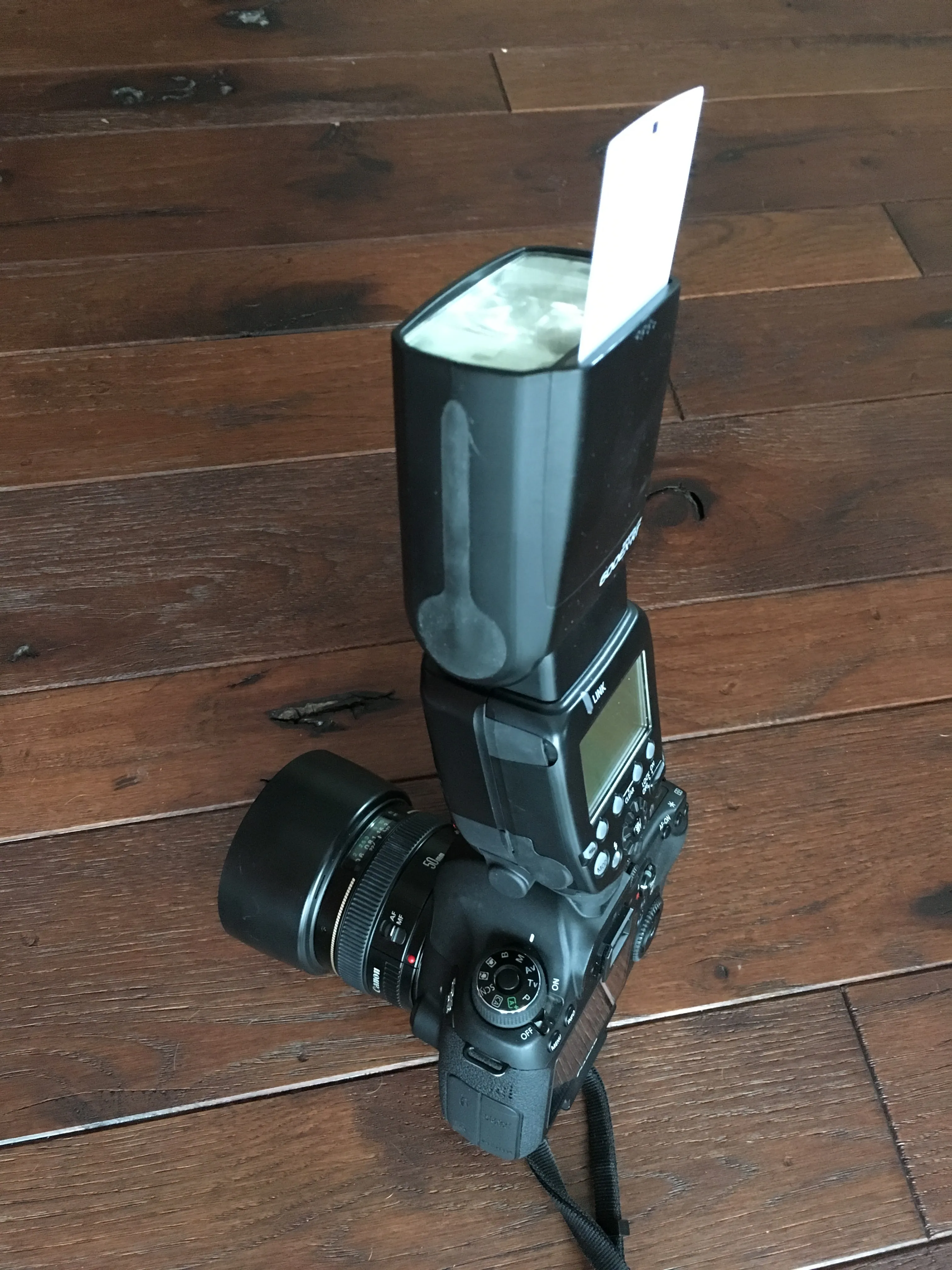 Canon DSLR with a speedlite and bounce card attached