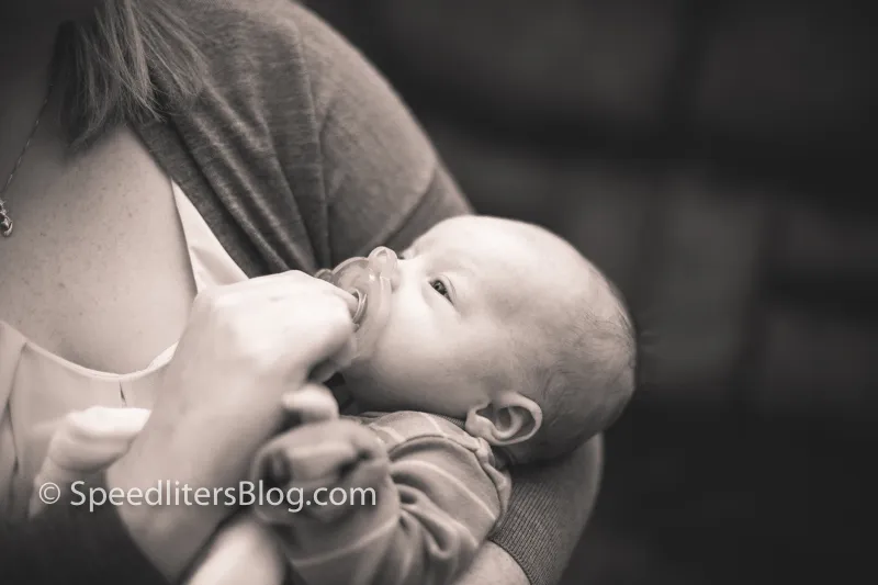 Black-and-white photo of a mother feeding her newborn a bottle