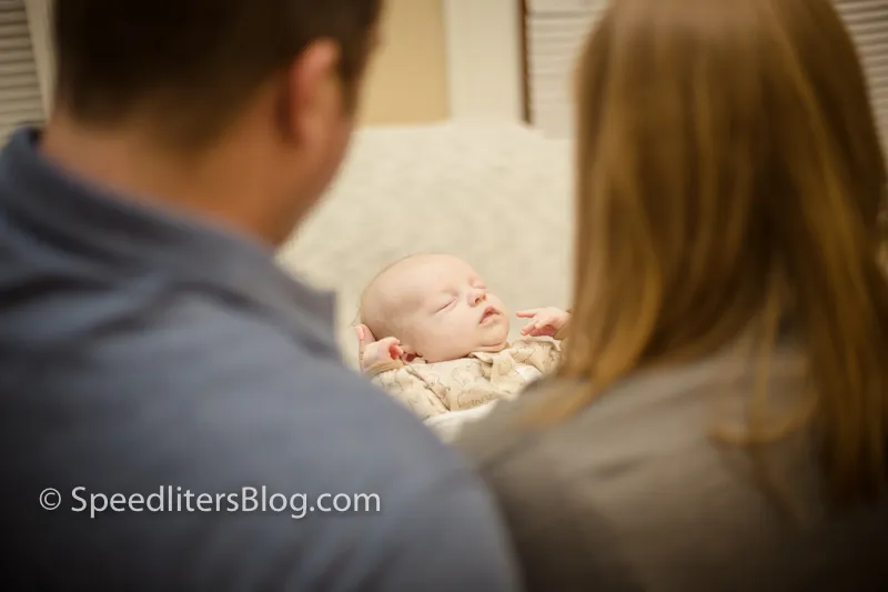 Parents looking down at their sleeping newborn, shot over their shoulders