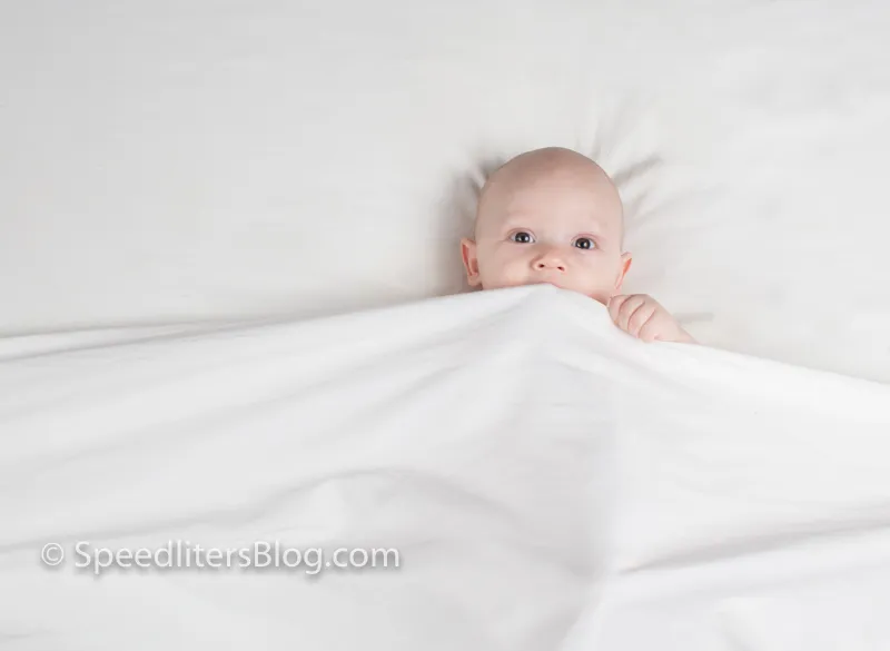 Baby peeking over a white sheet