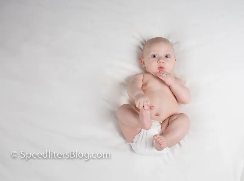 Baby lying on white sheets looking at the camera