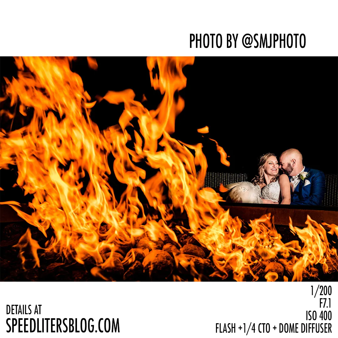 Couple sitting behind a roaring bonfire, flames filling the frame, by SMJ Photography
